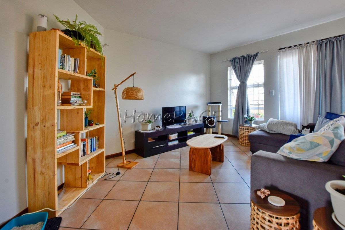 A bright living room featuring neutral tiled flooring and large windows that provide ample natural light, creating a comfortable and inviting living space.