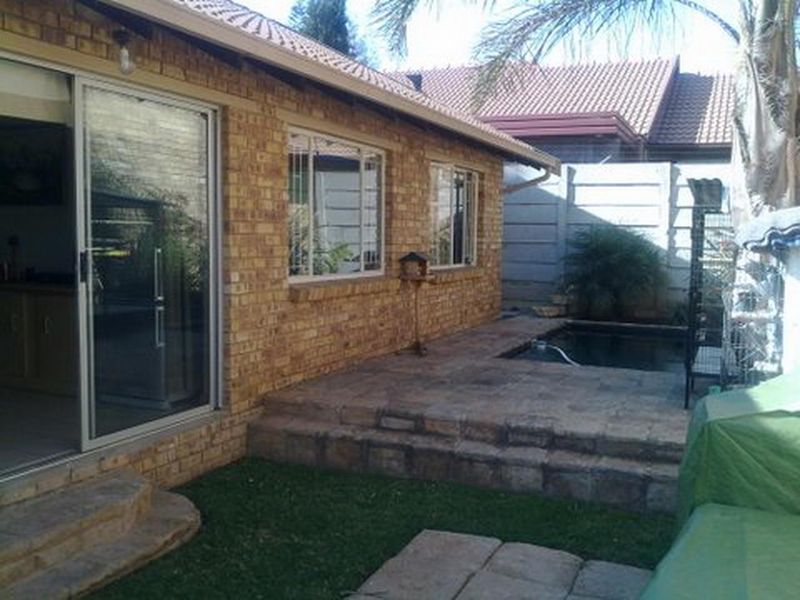 Rear exterior view of a brick townhouse featuring a paved patio area, a small plunge pool, and sliding door access to the interior.