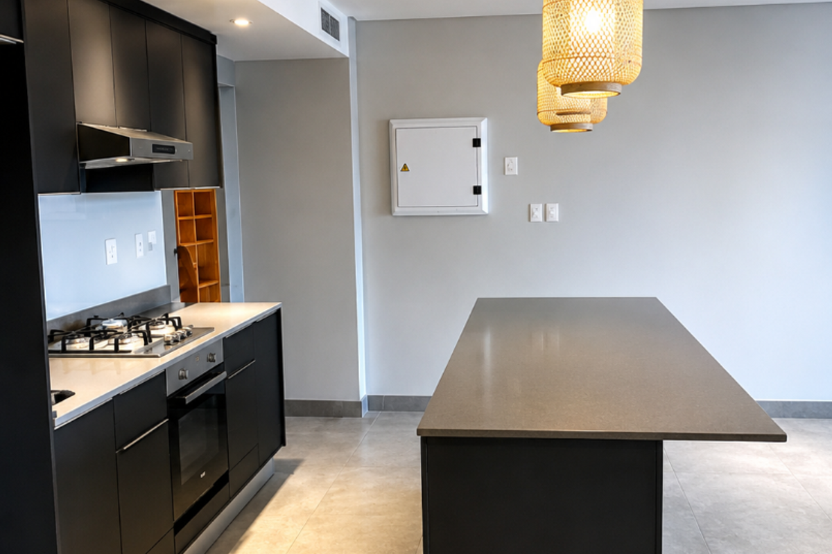 Modern kitchen featuring sleek black cabinetry, a central island with stone countertops, built-in gas hob, oven, and integrated extractor fan.