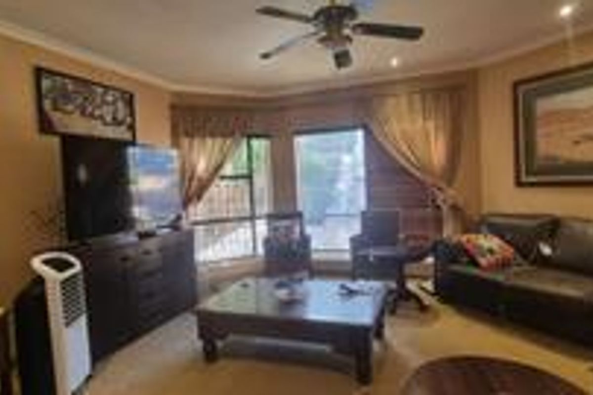 A comfortable living room featuring a bay window, ceiling fan, and recessed lighting, providing a functional and inviting space for relaxation.
