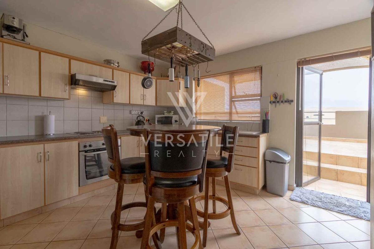 Functional kitchen featuring light wood cabinetry, built-in oven, extractor fan, and tiled flooring with direct access to an outdoor patio area.