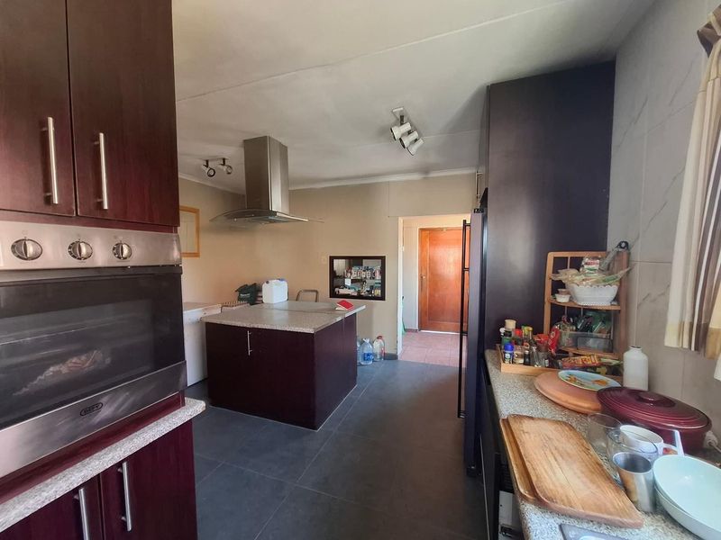 A functional kitchen featuring dark wood cabinetry, stone countertops, a central island, and a built-in oven with an overhead extractor fan.