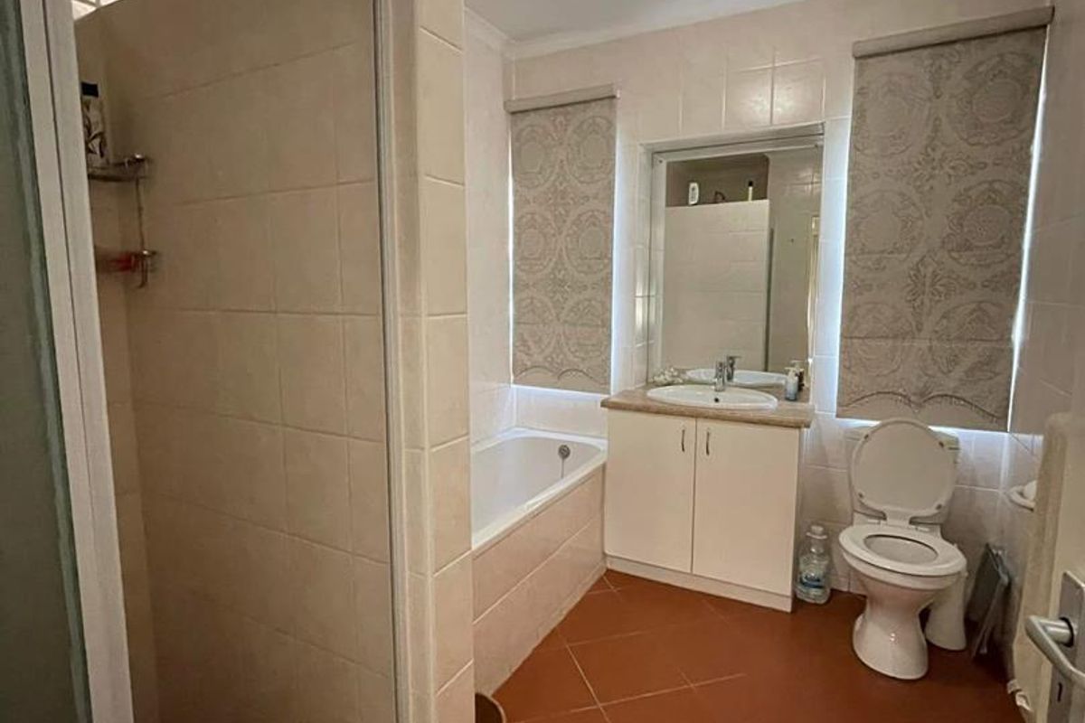 A functional bathroom featuring a separate shower enclosure, a built-in bathtub, a vanity basin, and a toilet with neutral wall tiling.