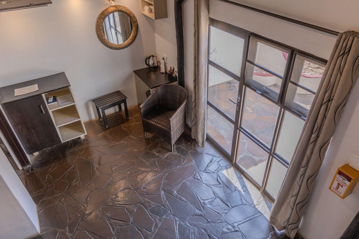A cozy lodge interior featuring natural stone flooring, a built-in fireplace flue, and large glass sliding doors providing direct access to a paved patio area.