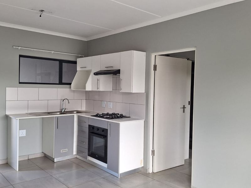 Modern kitchen featuring built-in cabinetry, gas hob, oven, extractor fan, and tiled backsplash, presented in a clean, empty space ready for occupancy.