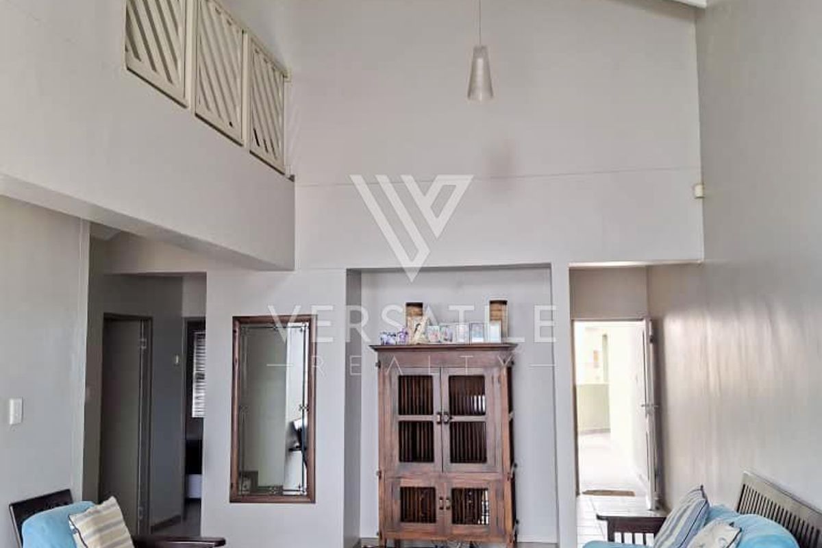 Spacious living area featuring high vaulted ceilings, exposed beams, and a mezzanine level overlooking the main lounge space.
