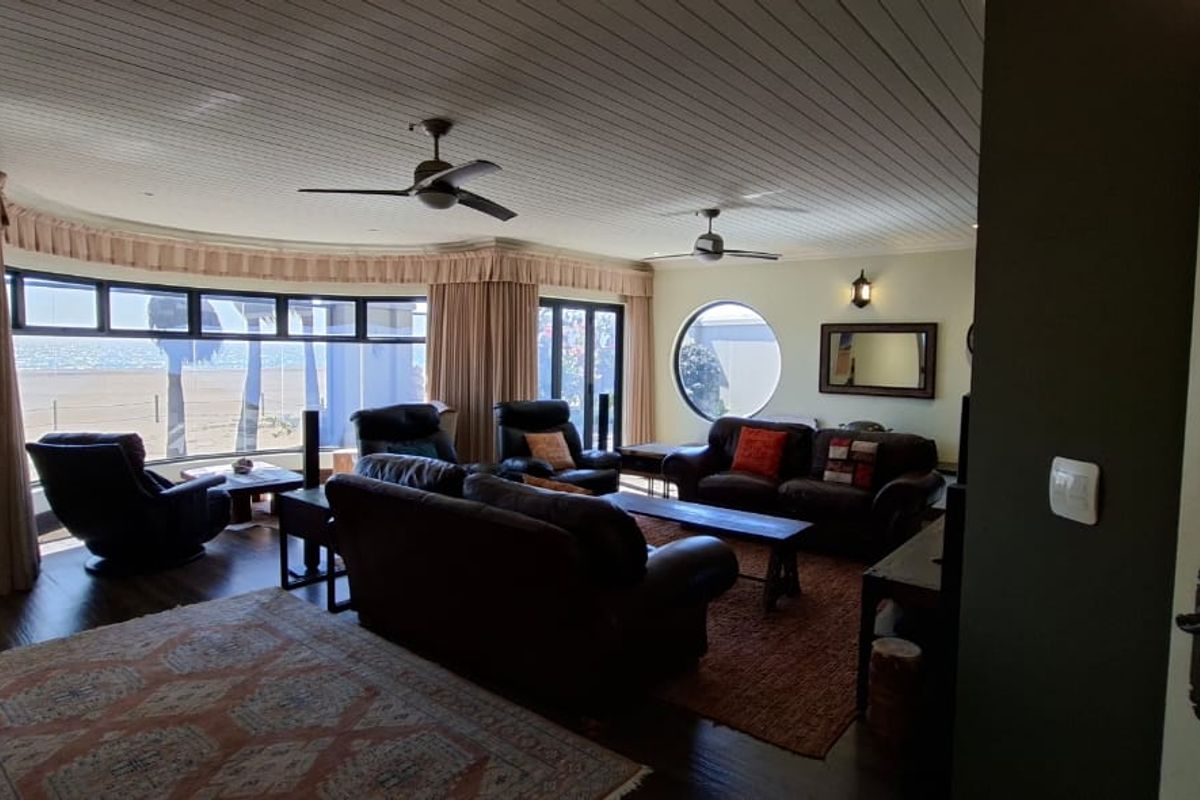 Spacious living room featuring a timber ceiling, ceiling fans, and unique curved and circular windows offering natural light and views.