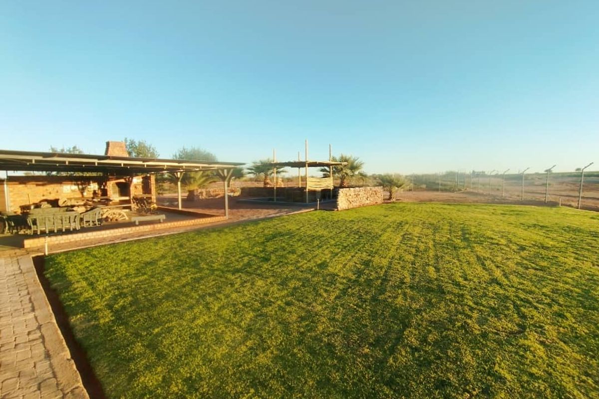 Spacious rear garden featuring a covered patio with a built-in braai, stone wall accents, and a well-maintained lawn area.