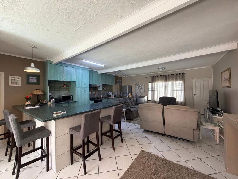 Open-plan living area featuring a kitchen with built-in cabinetry, a breakfast island, and tiled flooring throughout the combined space.