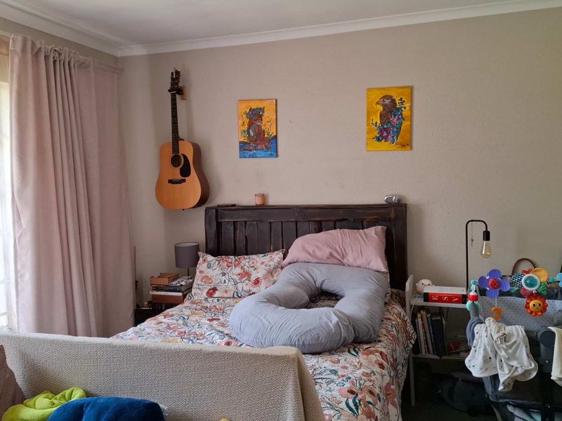 A cozy bedroom featuring a large window with curtains, neutral wall tones, and classic coving detail.