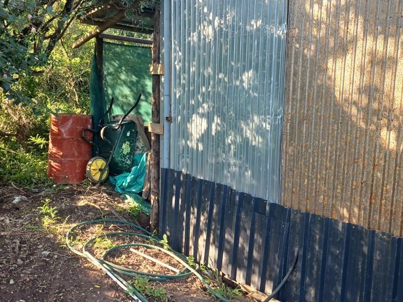 Exterior view of a utility structure featuring corrugated metal cladding and timber supports, showing signs of weathering and corrosion.