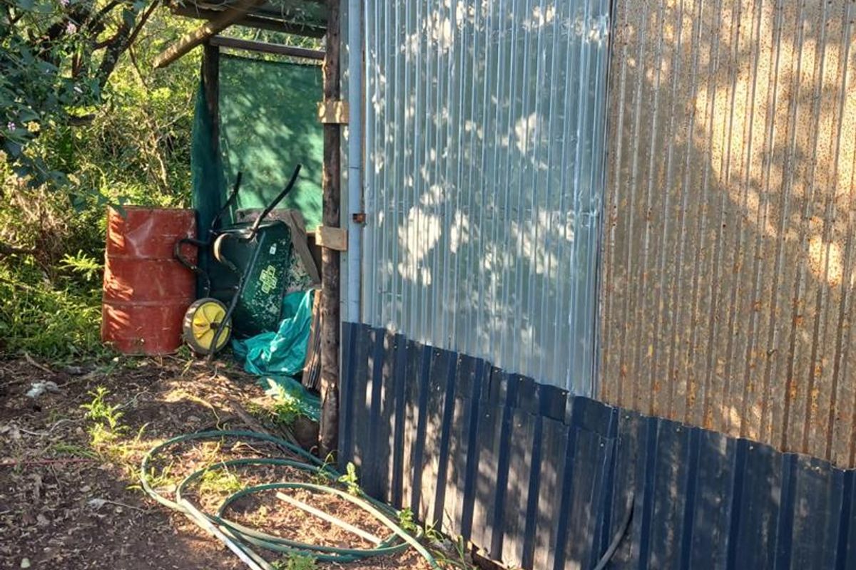 Exterior view of a utility structure featuring corrugated metal cladding and timber supports, showing signs of weathering and corrosion.