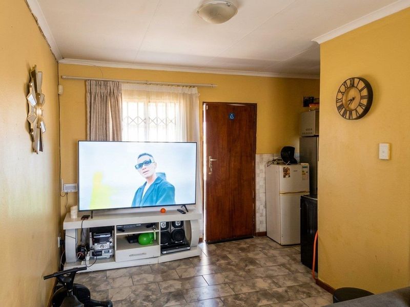 Open plan living area featuring tiled flooring and direct access to the exterior, requiring cosmetic updates to improve the overall aesthetic.