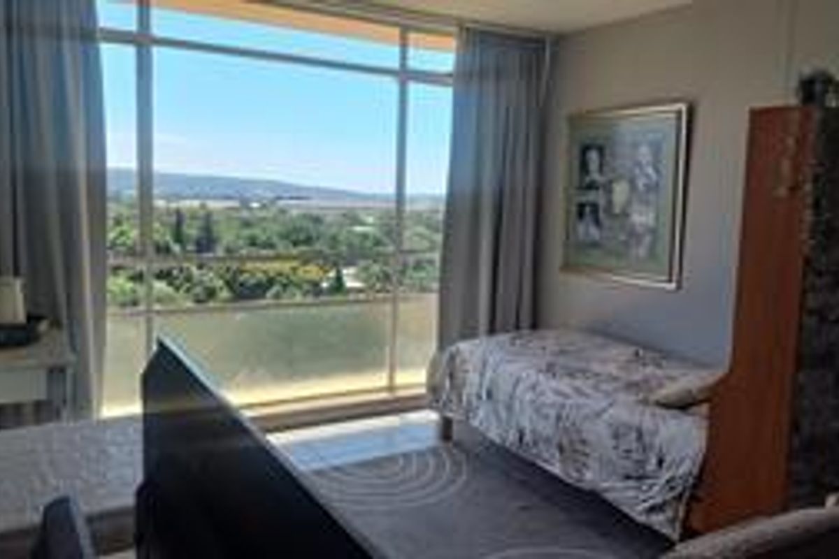 A bedroom featuring large floor-to-ceiling windows that provide ample natural light and expansive views of the surrounding landscape.