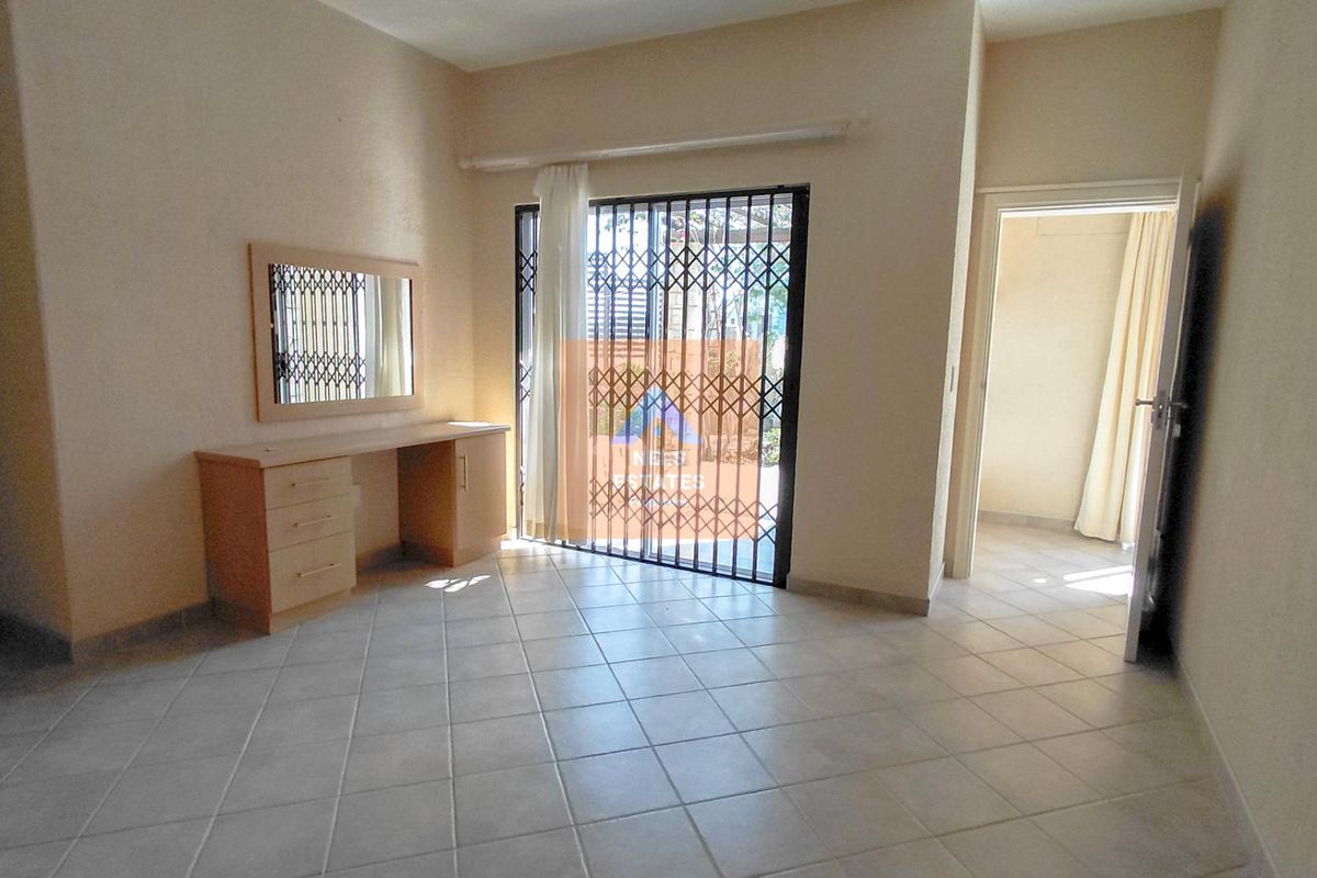 A bedroom featuring tiled flooring and a sliding door with a security gate, providing access to the exterior.