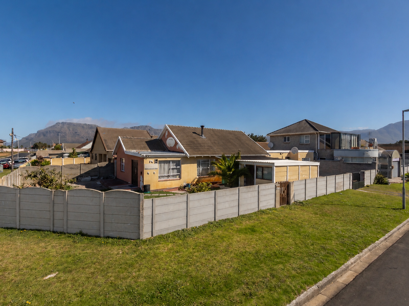 A detached single-story house featuring a tiled roof, chimney, and a secure precast concrete boundary wall, situated in a residential neighborhood with mountain views.