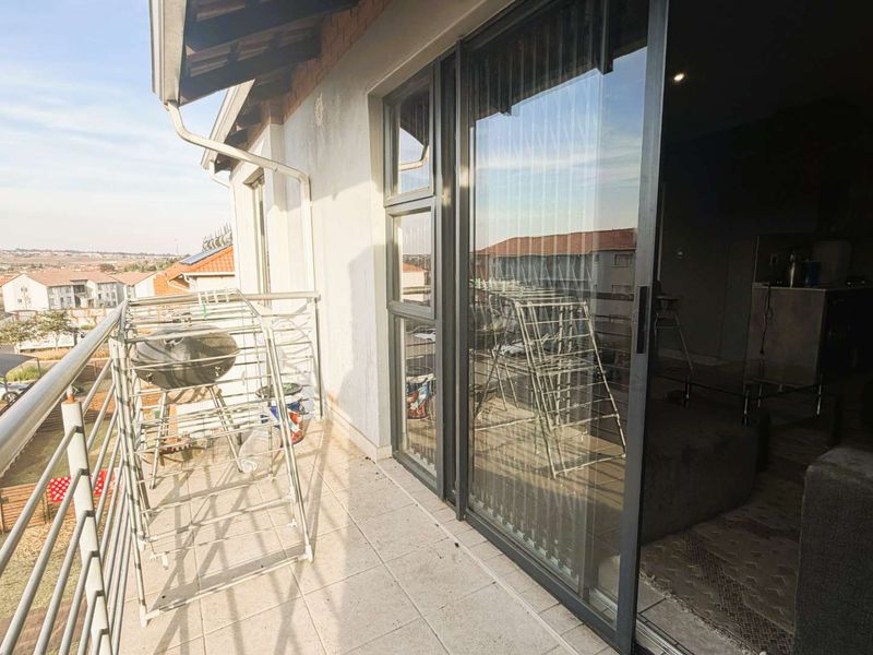 A balcony area featuring tiled flooring, metal railings, and large sliding glass doors providing access to the interior living space.
