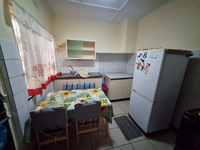A functional kitchen featuring basic cabinetry, tiled splashbacks, and tiled flooring, offering potential for modernization and aesthetic updates.