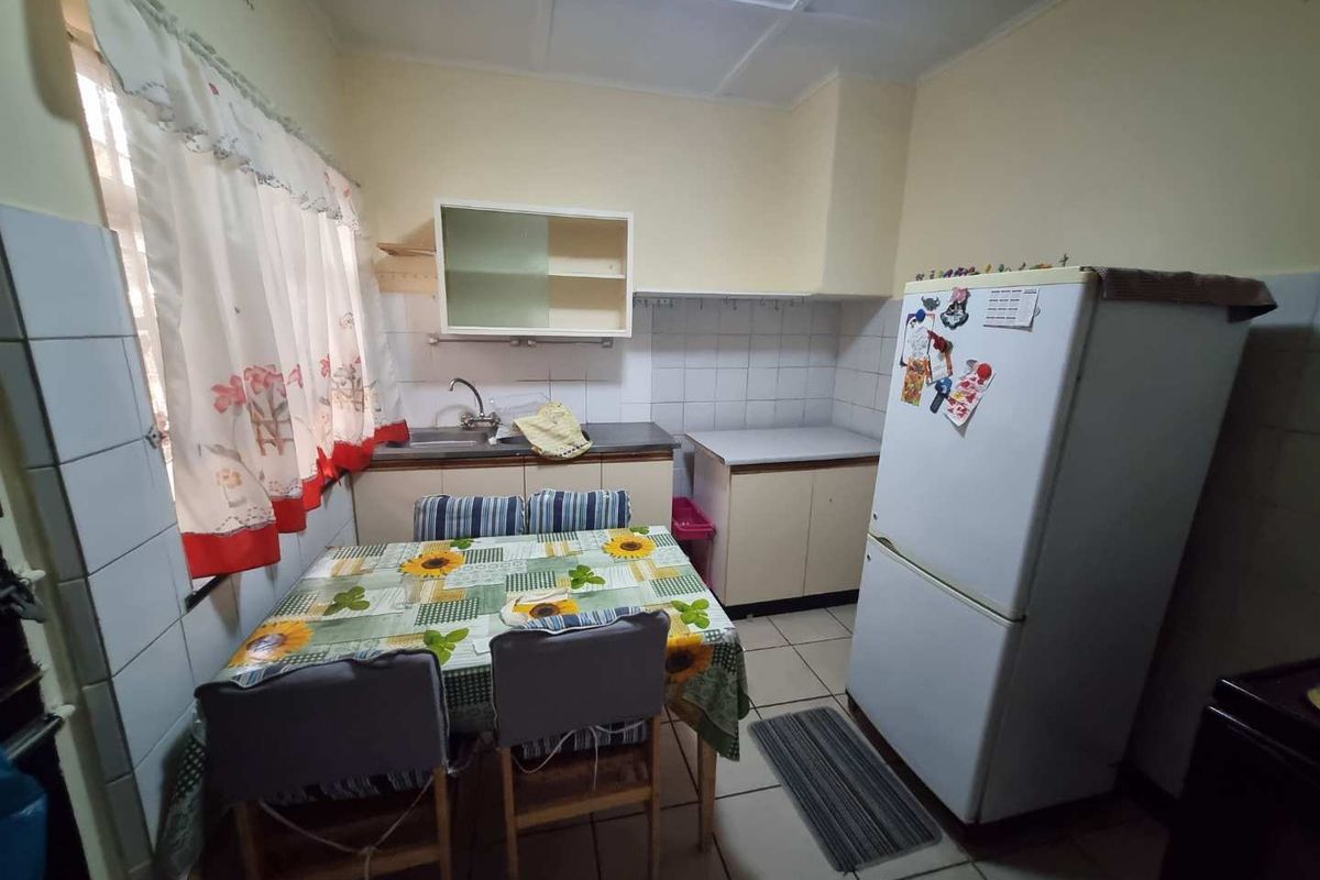 A functional kitchen featuring basic cabinetry, tiled splashbacks, and tiled flooring, offering potential for modernization and aesthetic updates.
