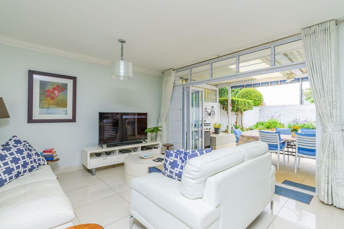 Bright living room featuring large glass sliding doors that open onto a covered patio and private garden area.