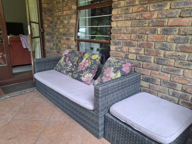 A covered patio area featuring exposed brick walls, tiled flooring, and direct access to the interior through a timber-framed door.