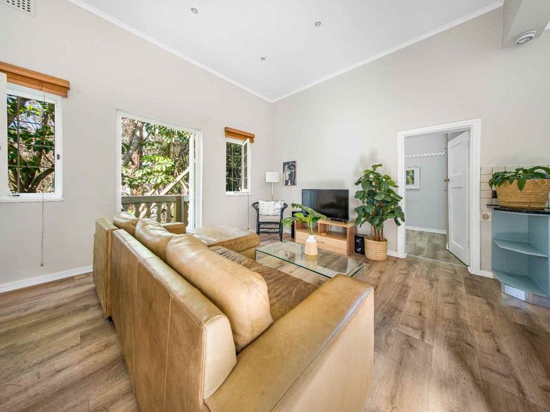 Bright living room featuring laminate flooring, recessed lighting, and direct access to a balcony through a glass door.