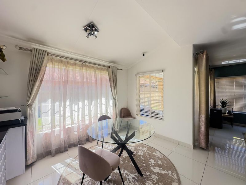 A bright dining area featuring tiled flooring, large windows with venetian blinds, and neutral wall finishes, providing a functional space for meals.