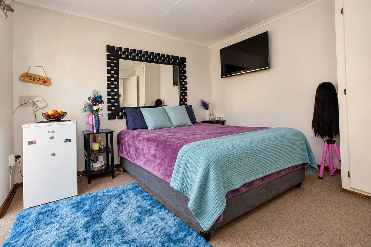 A functional bedroom featuring neutral walls, carpeted flooring, and built-in cupboard storage space.