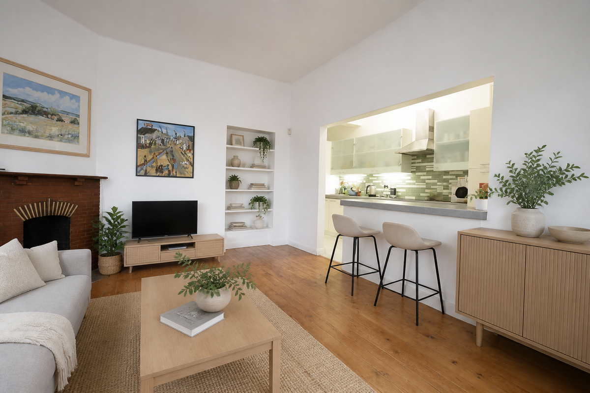 Open plan living area featuring timber flooring, a brick fireplace, built-in shelving, and a functional kitchen with a breakfast bar.