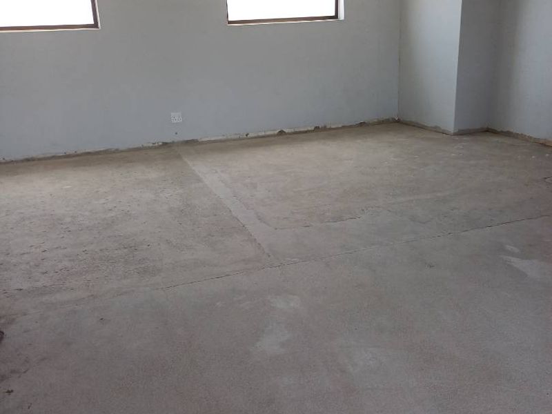 An empty, unfinished retail space featuring exposed concrete flooring, painted walls, and large windows, ready for custom fit-out.