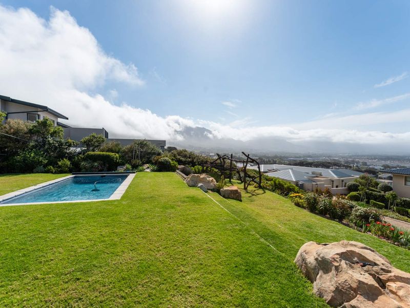 A well-maintained swimming pool set within a landscaped garden, featuring expansive mountain and valley views.
