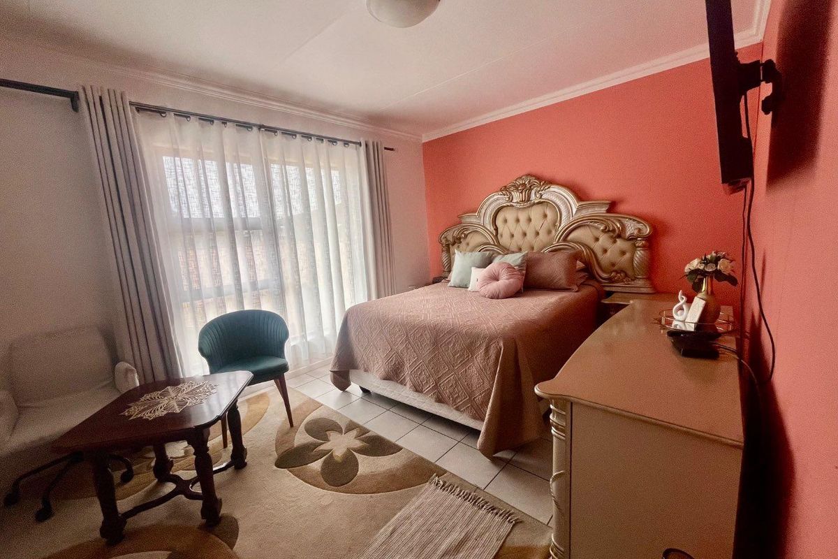A bedroom featuring tiled flooring, a large window with curtain tracks, and a ceiling-mounted light fixture.