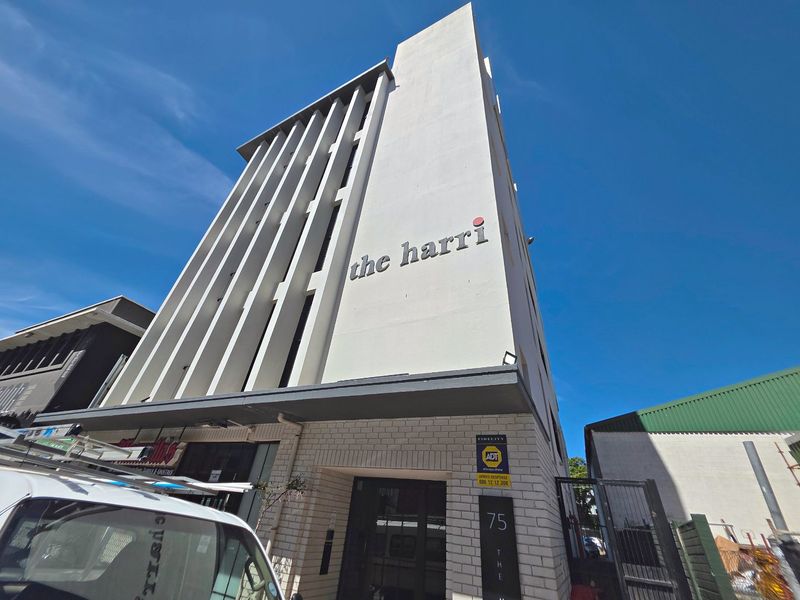 Exterior view of The Harri apartment building facade featuring modern architectural design and prominent building signage.