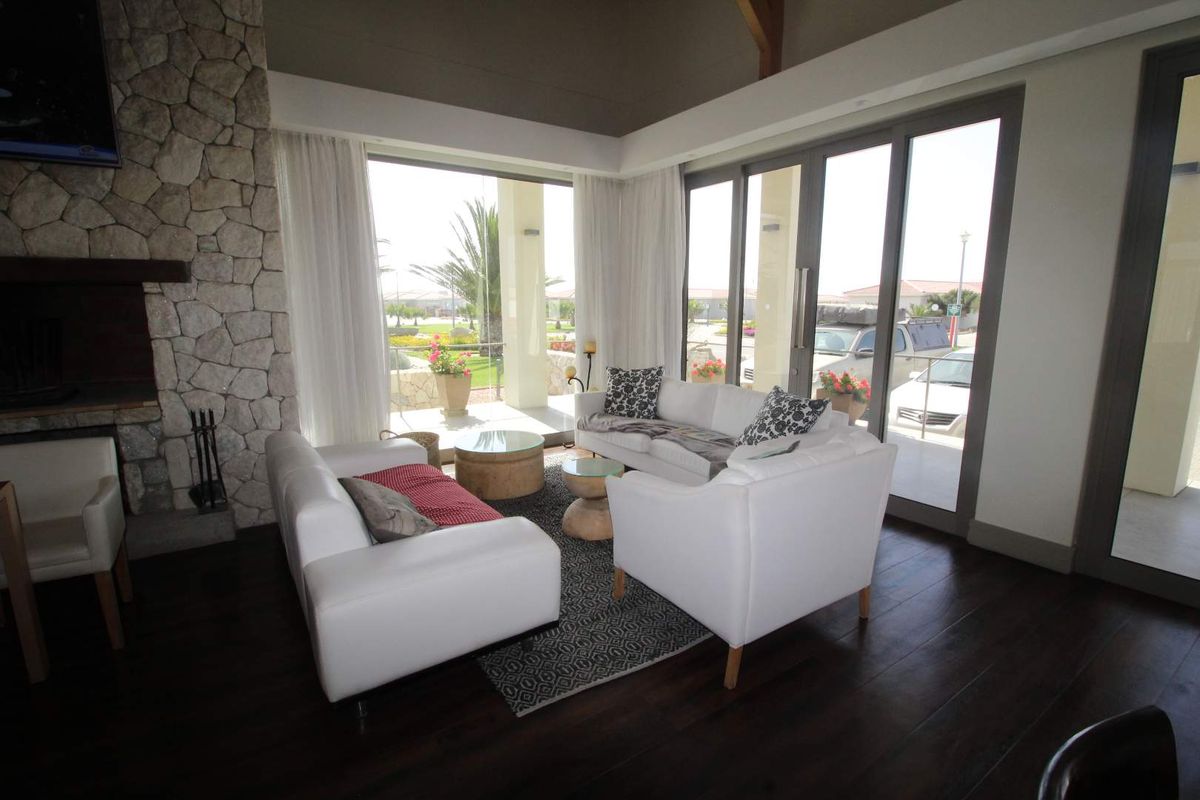 Spacious living room featuring a prominent stone-clad fireplace, dark timber flooring, and large glass sliding doors opening to an outdoor patio area.