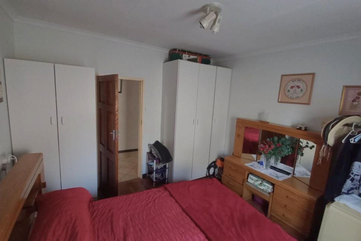 A functional bedroom featuring built-in white cupboards, timber door, and standard ceiling lighting, offering a practical layout for personal living space.
