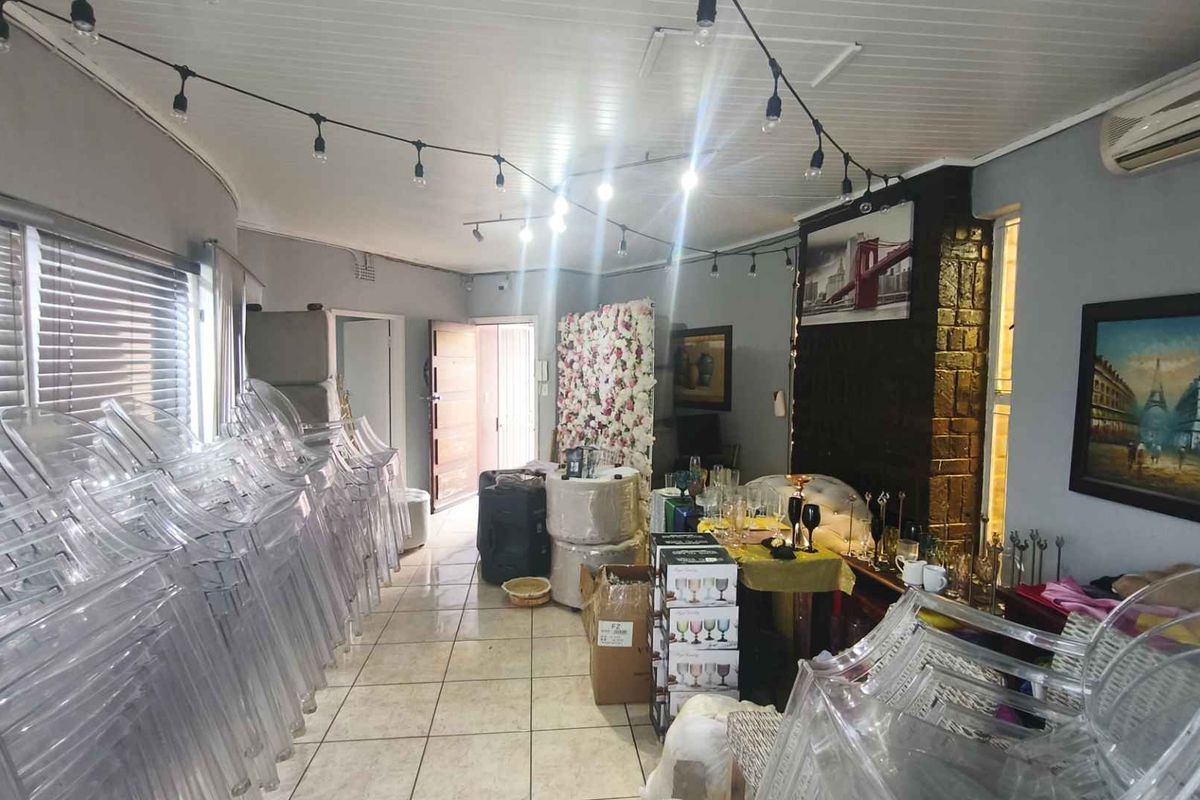 A spacious living area featuring tiled flooring, a stone-clad feature wall, and a tongue-and-groove ceiling with integrated air conditioning.