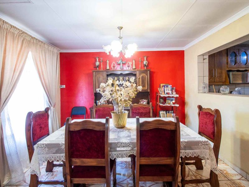 A dining room featuring tiled flooring and a convenient pass-through window connecting to the kitchen area.