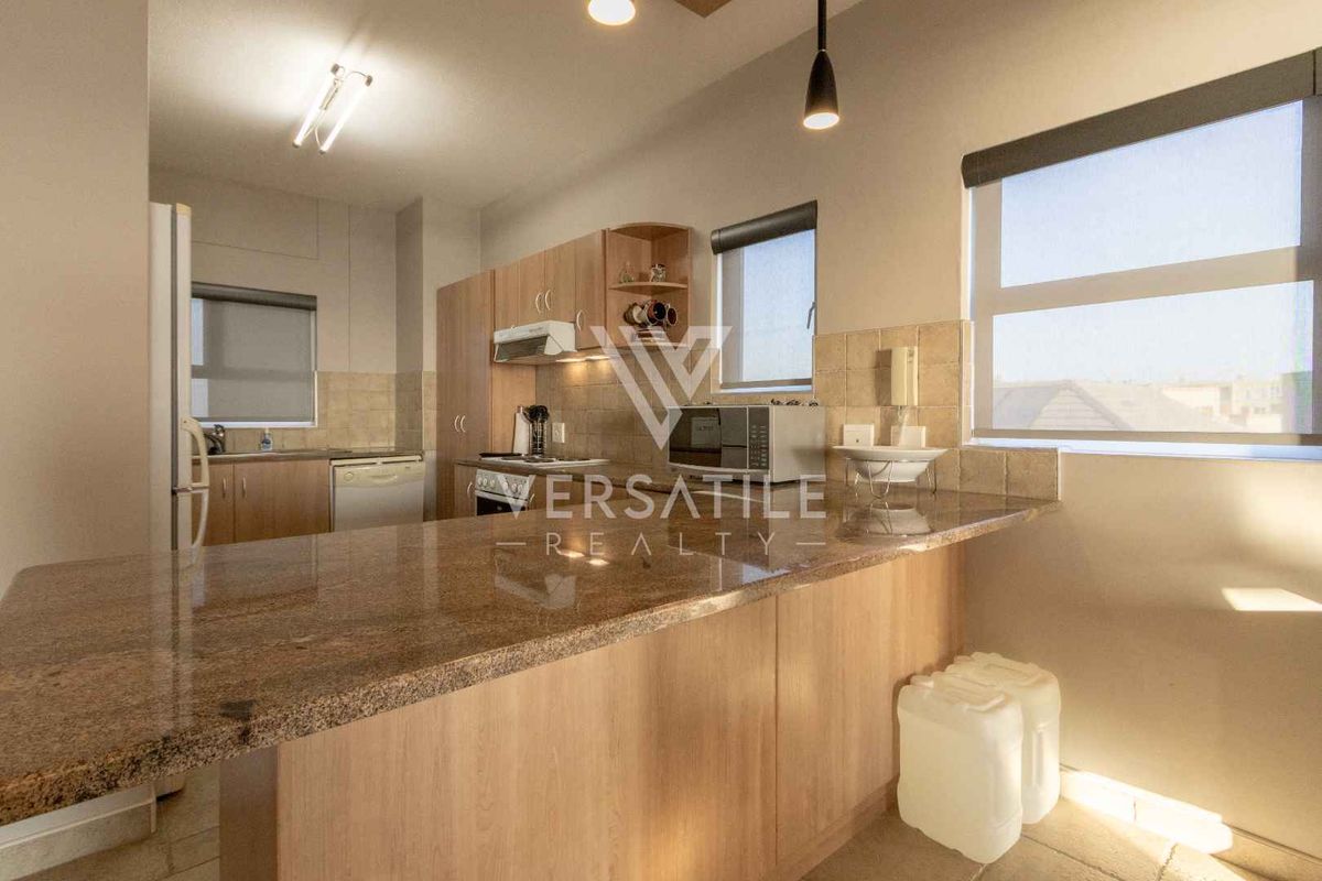 A functional kitchen featuring light wood cabinetry, granite countertops, a breakfast bar, and a tiled backsplash with ample natural light.