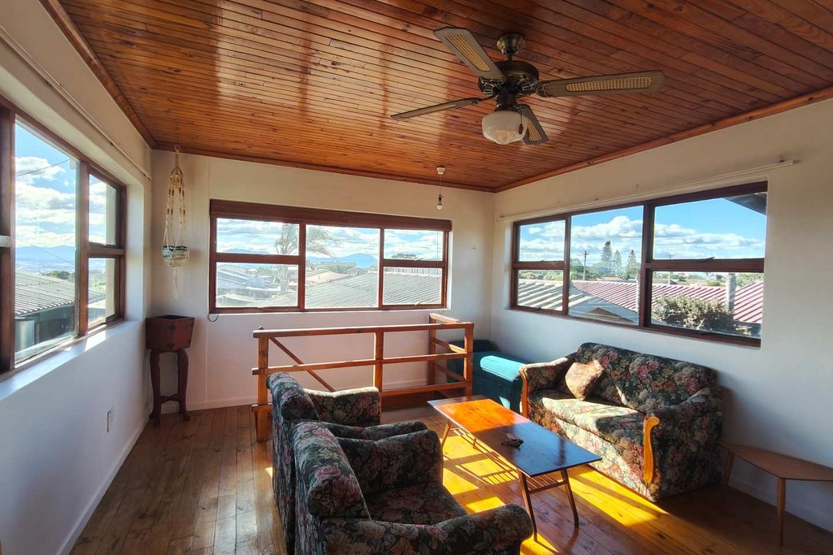 Bright living area featuring timber-clad ceilings, polished wooden floors, and large windows offering expansive neighbourhood views.