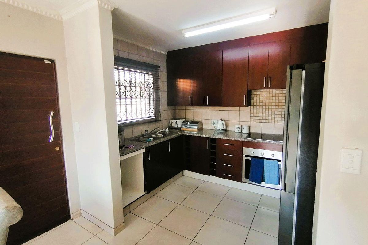 A functional kitchen featuring dark wood cabinetry, granite countertops, tiled backsplash, and built-in oven with hob.