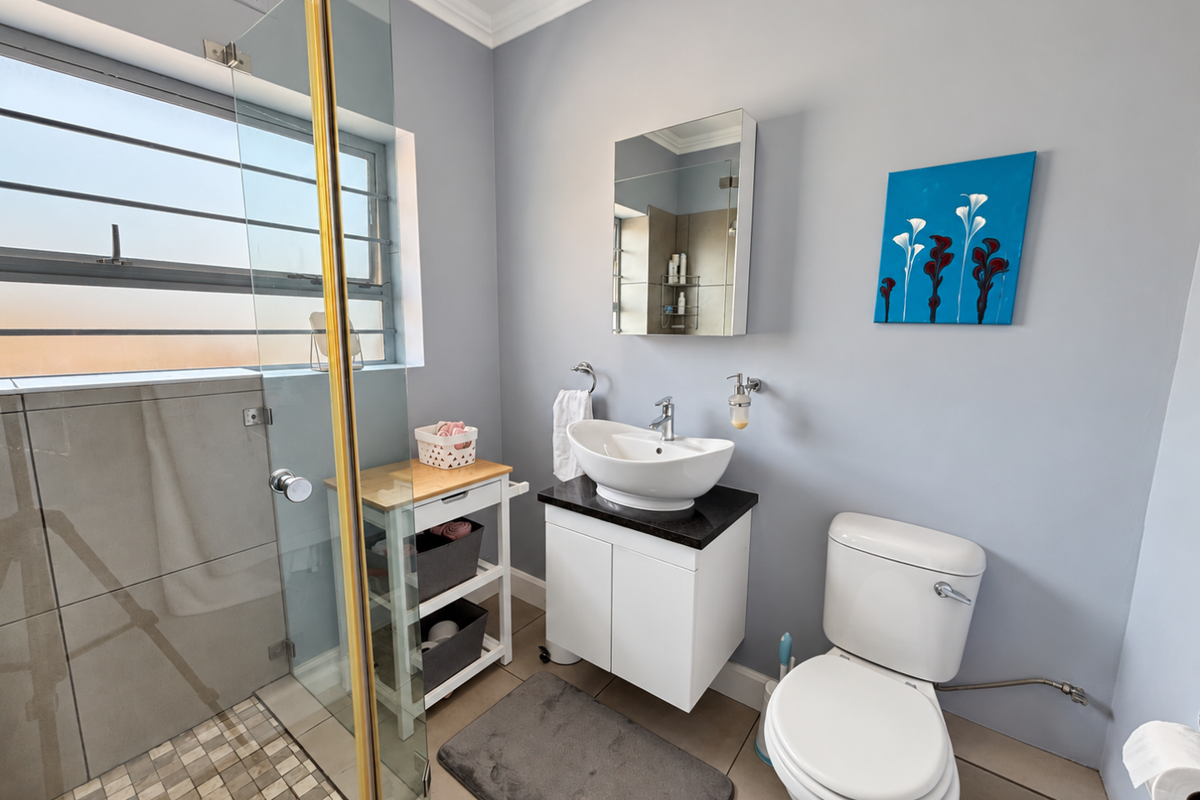 A well-maintained bathroom featuring a glass-enclosed shower, modern vessel sink vanity, wall-mounted medicine cabinet, and a standard toilet.