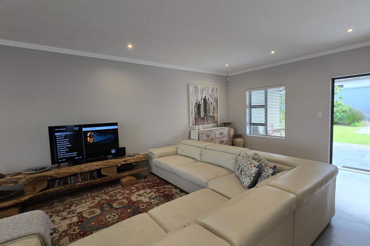 A bright and spacious living room featuring neutral walls, recessed downlighting, and direct access to an outdoor patio area.