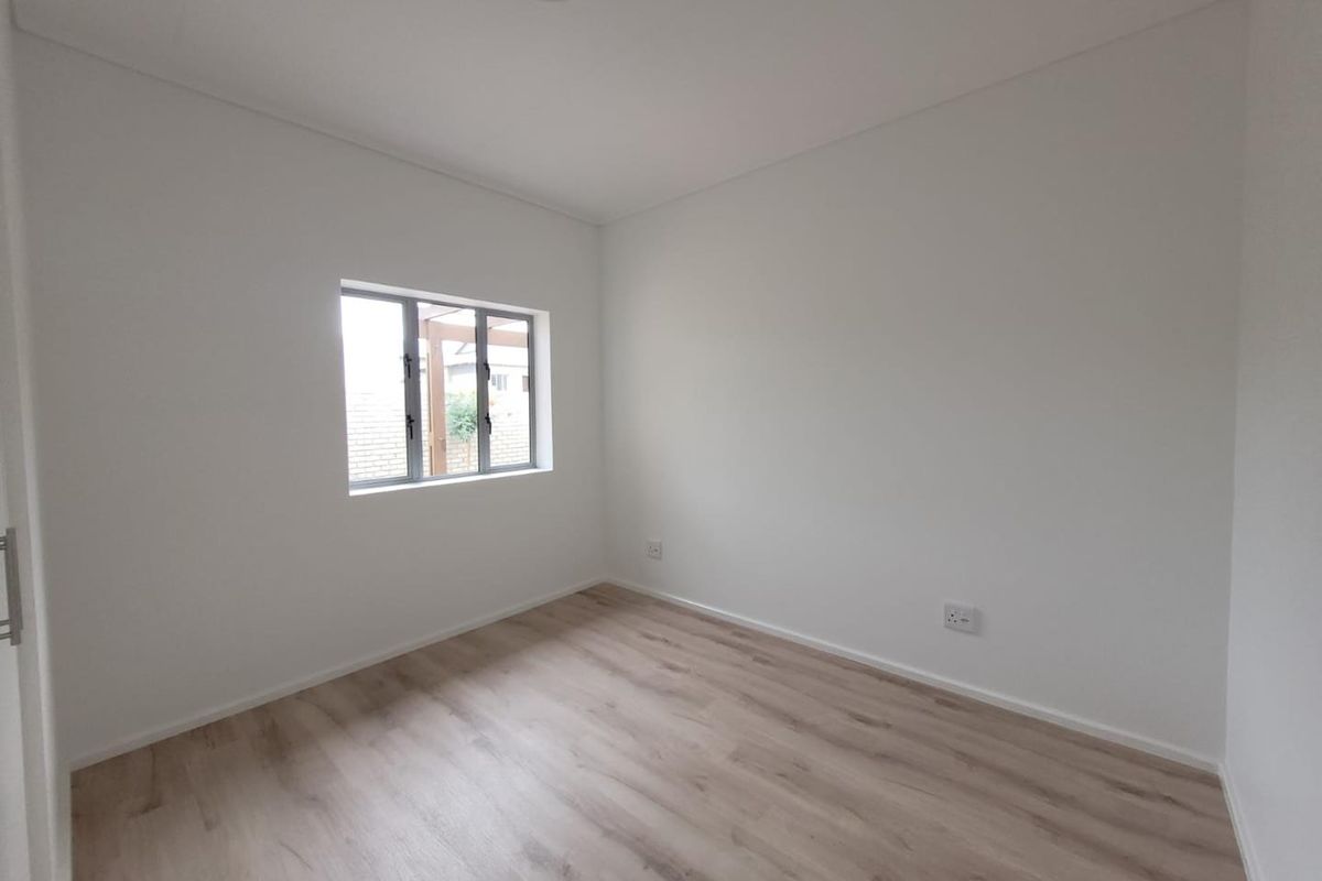 A bright, empty bedroom featuring neutral walls and modern light wood-look flooring, providing a clean and versatile space ready for personalization.