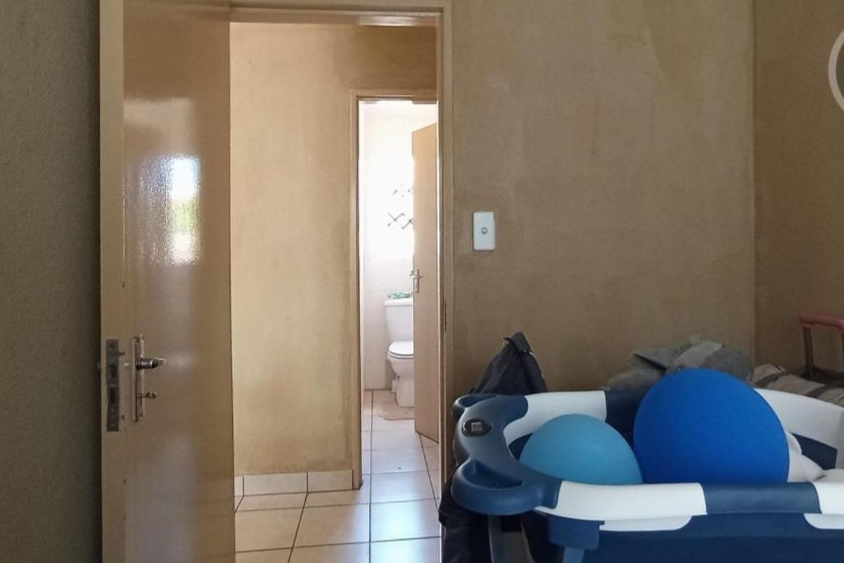 Interior view showing a bedroom leading into an adjacent bathroom with tiled flooring and basic door fixtures.
