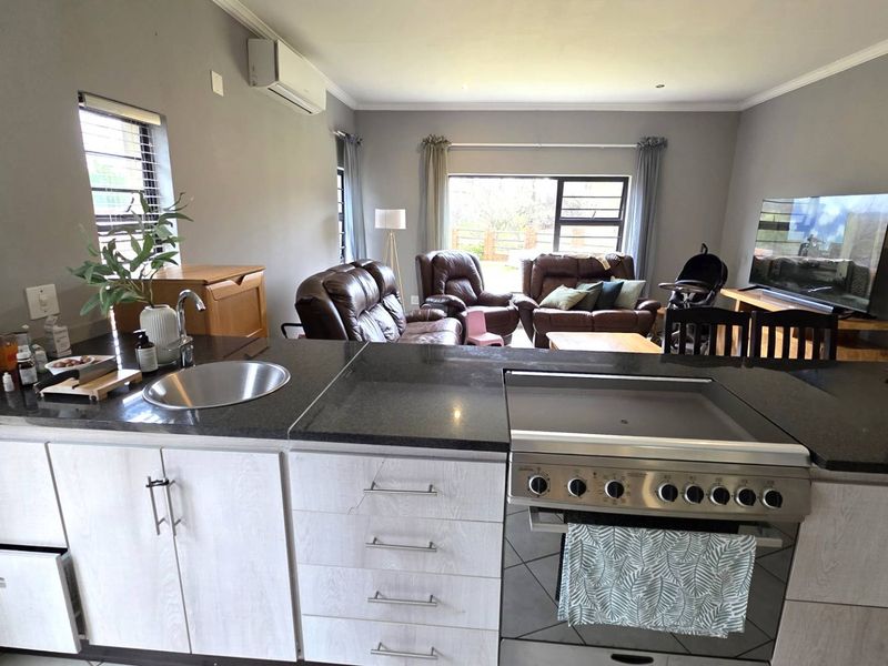 Open-plan living area featuring a modern kitchen with granite countertops, stainless steel appliances, and a spacious lounge area with air conditioning.