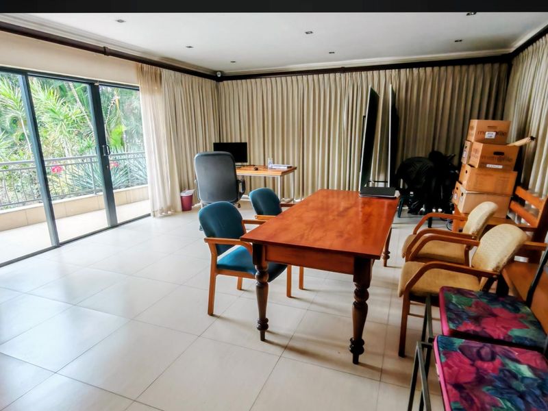 Spacious living area featuring large sliding glass doors leading to a balcony, neutral tiled flooring, and recessed ceiling lighting.