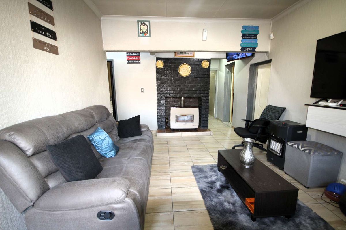 A living room featuring tiled flooring and a central brick fireplace, providing a functional and cozy space for relaxation.