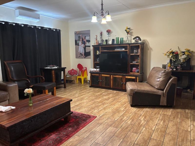 A living room featuring tiled flooring, a wall-mounted air conditioning unit, and a central ceiling light fixture.