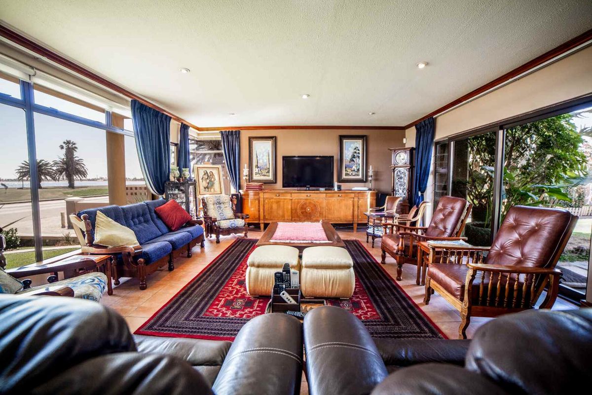 Spacious living room featuring large floor-to-ceiling windows, tiled flooring, and sliding glass doors providing access to the outdoor area.