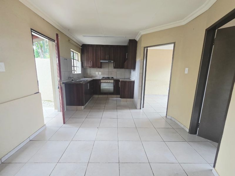 A functional kitchen featuring dark wood cabinetry, built-in oven and hob, tiled flooring, and direct access to the exterior.
